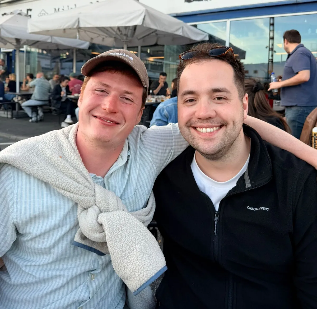 Will and Jonny outdoors in Copenhagen, arms round each other, laughing